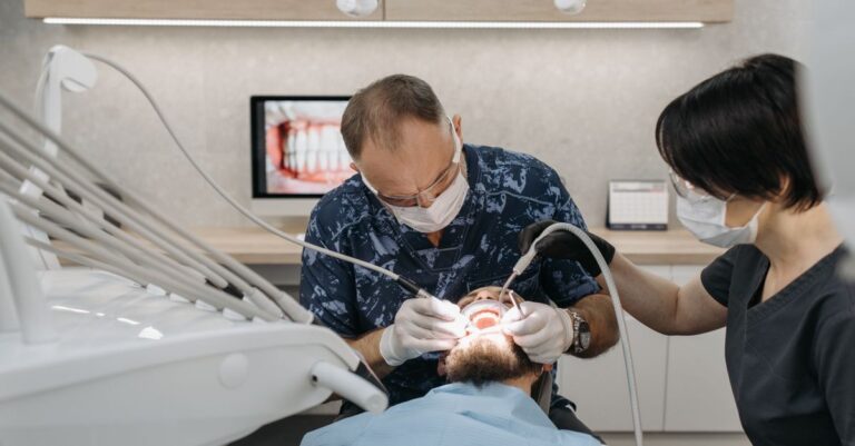 Dentista y asistente realizando un procedimiento dental en un paciente en una clínica moderna.